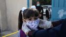 Seorang guru menyesuaikan posisi masker seorang pelajar di sekolah pada hari pertama tahun ajaran baru di kamp pengungsi Al-Amari di Kota Ramallah, Tepi Barat (6/9/2020). Pelajar Palestina memulai tahun ajaran baru setelah belajar di rumah selama enam bulan akibat Covid-19. (Xinhua/Nidal Eshtayeh)