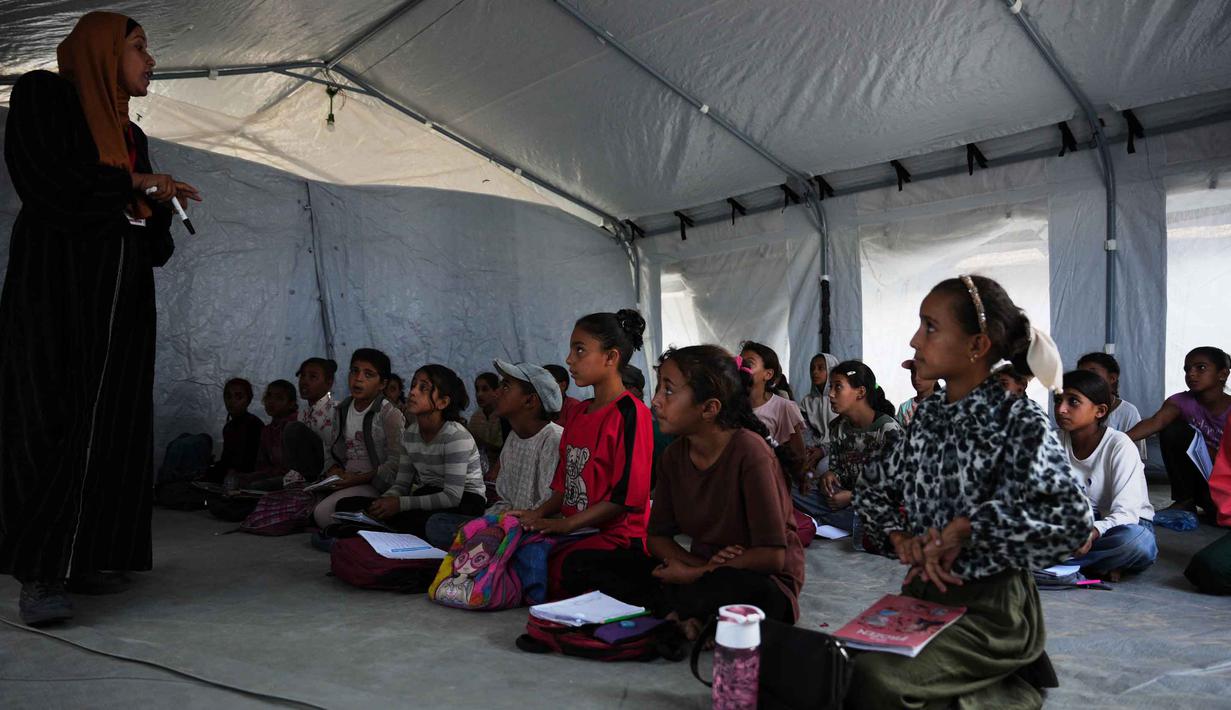 Kegiatan belajar mengajar dilakukan di beberapa lokasi, seperti di sekolah Al Hassaina, Nuseirat dan sekolah Al-Kamaliya al-Othmanya, kota tua Gaza. Tampak dalam foto, para siswa Palestina mengikuti pelajaran di dalam tenda yang didirikan di pantai di Khan Younis, Jalur Gaza, Rabu, 12 November 2025. (AP Photo/Abdel Kareem Hana)