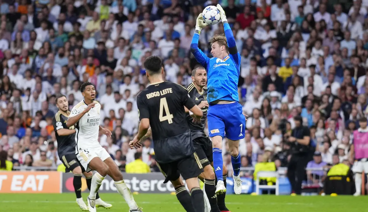 Kiper Union Berlin, Frederik Ronnow, menangkap bola saat melawan Real Madrid dalam matchday 1 Grup C Liga Champions 2023/2024, di Stadion Santiago Bernabeu, Madrid, Rabu (20/9/2023). Leonardo Bonucci selalu sigap berada di sisi kiper Union Berlin untuk mengantisipasi jatuhnya bola di sekitar pertahanan. (AP Photo/Manu Fernandez)