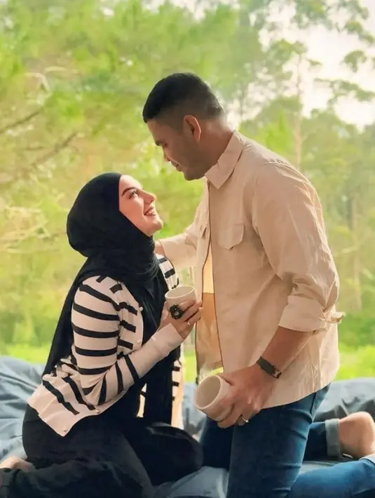 Sebagai pengantin baru, Irish Bella tampil mengenakan cardigan putih garis hitam dipadukan kerudung dan inner dress warna senada. Suami tampil dengan outer dipadukan celana denim. [@_irishbella_]