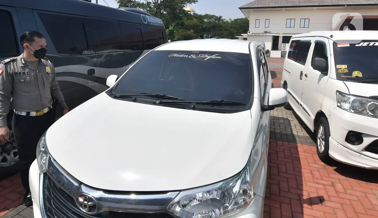 Petugas polisi memeriksa mobil travel gelap yang disita di halaman Polres Metro Kabupaten Bekasi, Jawa Barat, Senin (10/5/2021). Satlantas Polres Metro Bekasi mengamankan 32 travel gelap yang masih beroperasi saat larangan mudik dari tanggal 6-17 Mei 2021. (Liputan6.com/Herman Zakharia)