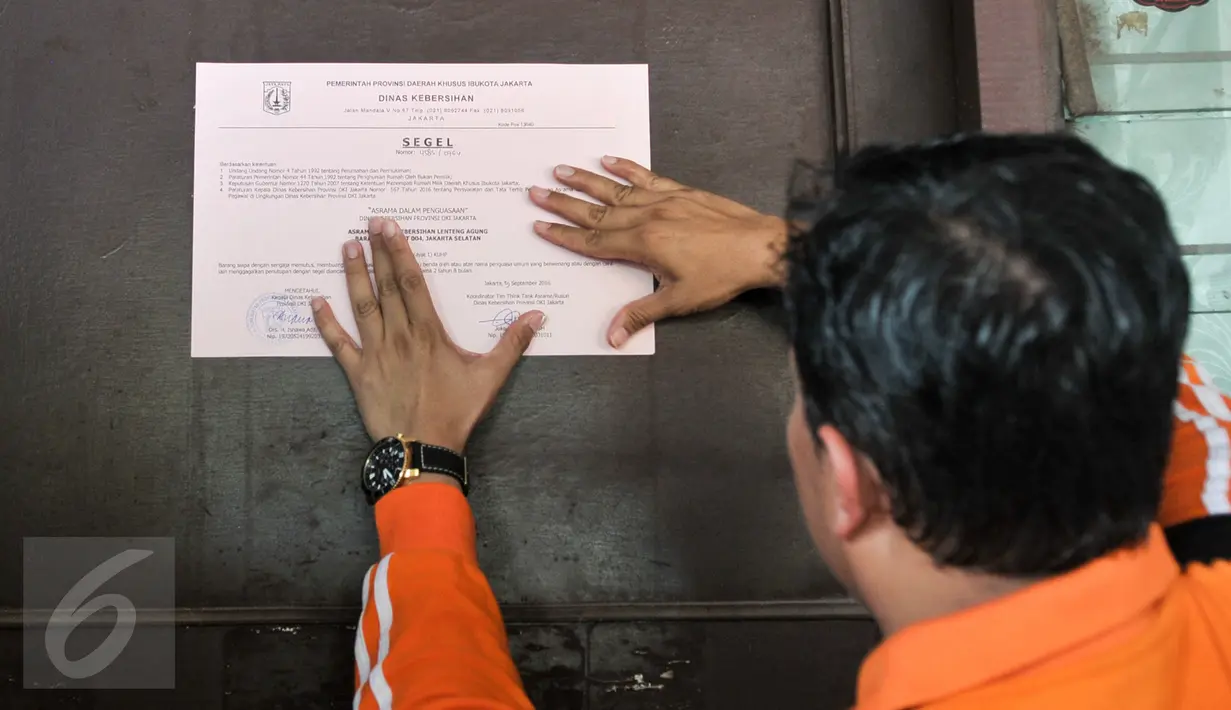 Kepala Dinas Kebersihan DKI Isnawa Adji menempelkan kertas penyegelan salah satu unit di asrama Dinas Kebersihan di Lenteng Agung, Jakarta, Jumat (30/9). Penyegelan sesuai dengan peraturan mengenai penempatan rumah dinas (Liputan6.com/Yoppy Renato)