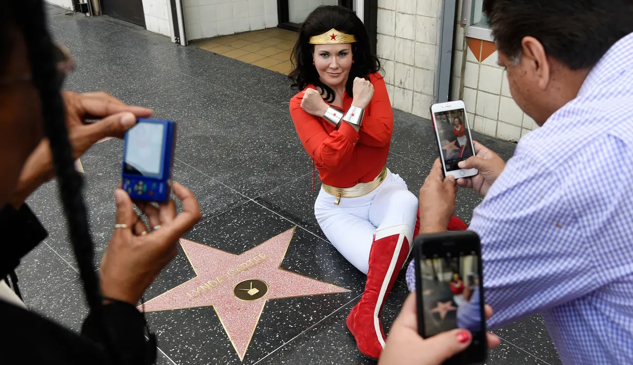 Penggemar mengenakan kostum Wonder Woman berpose di bintang Hollywood Walk of Fame aktris Lynda Carter di Los Angeles (3/4). Lynda Carter merupakan aktris yang memerankan serial televisi Wonder Woman tahun 1970-an. (Chris Pizzello / Invision / AP)