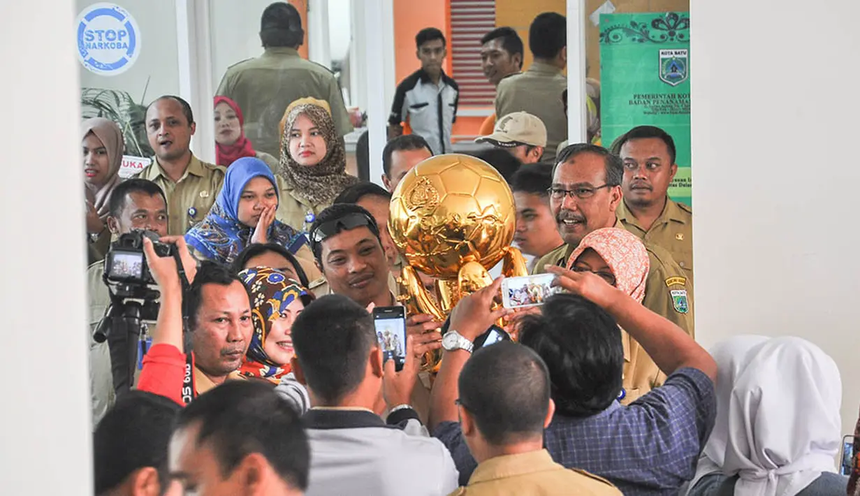 Para pegawai Pemerintah Kota Batu berebut foto dengan trophy Piala Bhayangkara 2016 di Malang, Jawa Timur, Selasa (11/4/2016). Kunjungan Arema Cronus ke Pemkot Batu menghasilkan bonus 100 juta rupiah. (Bola.com/Iwan Setiawan)