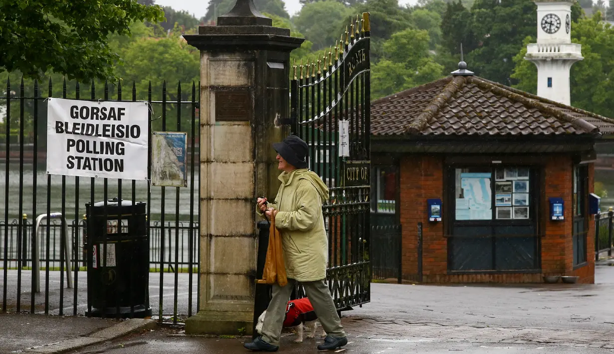 Seorang wanita bersama anjingnya setelah memberikan suara dalam pemilu parlemen Inggris di sebuah TPS di Roath Park Lake, Wales, Kamis (8/6). Para pemilih mengajak anjingnya untuk menemani mereka mengambil bagian dalam Pemilu Inggris. (GEOFF CADDICK/AFP)