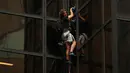 Seorang pria berambut gondrong memanjat gedung Trump Tower di New York, AS, Rabu (10/8). Pria yang tidak diketahui identitasnya itu nekat memanjat Menara Trump dengan tali dan cangkir hisap layaknya tengah memanjat tebing. (REUTERS/Lucas Jackson)