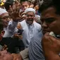 Imam Besar FPI, Habib Rizieq Shihab melambaikan tangan ke arah kerumunan massa yang menunggunya di gedung Dit Reskrimsus Polda Metro Jaya, Jakarta, Senin (23/1). Habib Rizieq akan diperiksa terkait ceramah lambang palu arit. (Liputan6.com/Faizal Fanani)