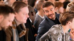 David Beckham saat menghadiri peragaan busana Musim Gugur/Musim Dingin 2020 Victoria Beckham dalam acara London Fashion Week di London, (16/2/2020). Beckham tampil dengan setelan jas hitam. (AFP/Daniel Leal-Olivas)