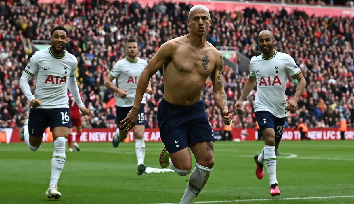 Pemain Tottenham Hotspur, Richarlison melakukan selebrasi dengan melepas jersey setelah mencetak gol penyeimbang ke gawang Liverpool di tambahan waktu babak kedua dalam pertandingan lanjutan English Premier League 2022/2023 yang berlangsung di Anfield stadium, Minggu (30/4/2023). (AFP/Paul Ellis)