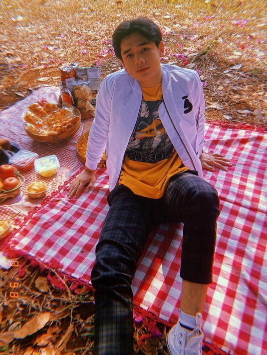 Bukan hanya mengunjungi suatu daerah, liburan Rayn Wijaya juga dihabiskan dengan piknik sederhana. Saat menikmati makanan dengan beralasan karpet di kebun, pemain sinetron Magic Cinta ini tampil stylish. Ia memadukan jaket dan kaus serta celana motif. (Liputan6.com/IG/@raynwijaya26)