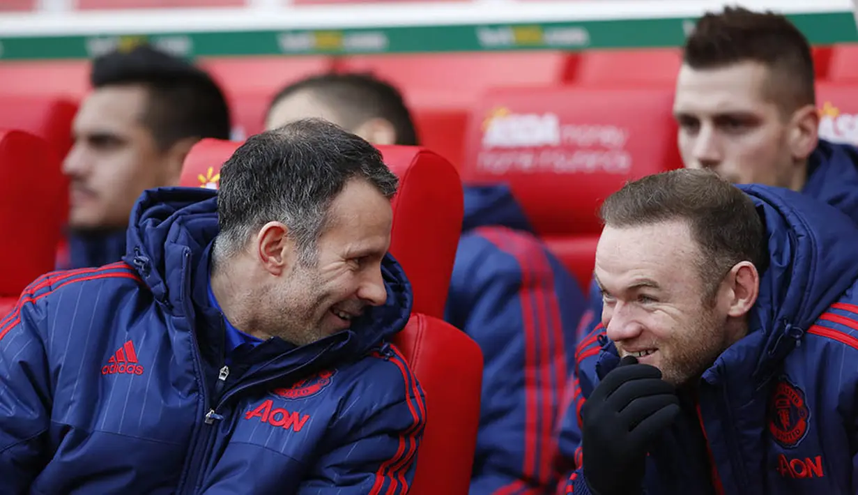Asisten pelatih MU, Ryan Giggs tertawa bersama Wayne Rooney saat berada di bangku cadangan kala MU bertanding melawan Stoke. (Reuters/Carl Recine)