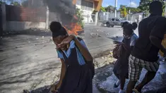 Pelajar berlari melewati barikade yang dibakar pengunjuk rasa saat protes menuntut pembebasan orang-orang yang diculik di Port-au-Prince, Haiti, 25 November 2021. Haiti mengalami peningkatan kasus penculikan terkait geng dan banyak yang menuntut uang tebusan. (AP Photo/Odelyn Joseph)