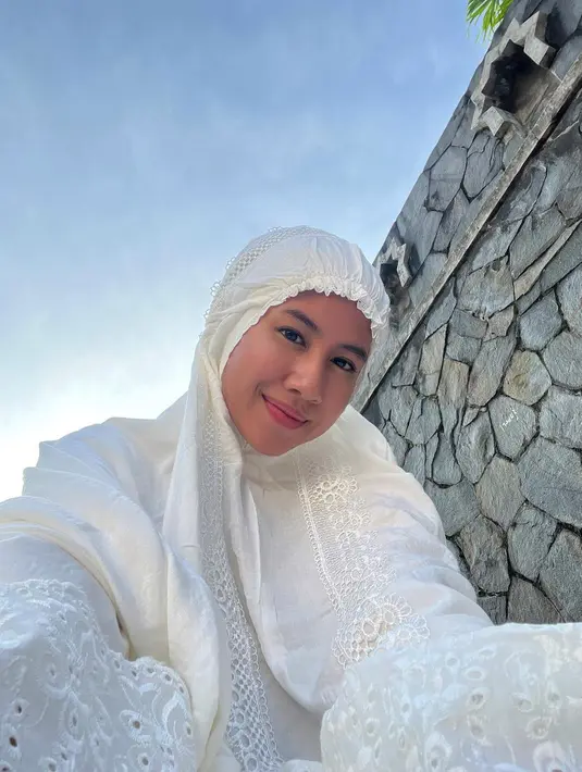 Shenina Cinnamon pamer bare face dengan mukena putih berenda saat Sholat Ied. Di balik mukenanya, ia mengenakan atasan pleated shimmer yang jadi tren. [@sheninacinnamon]