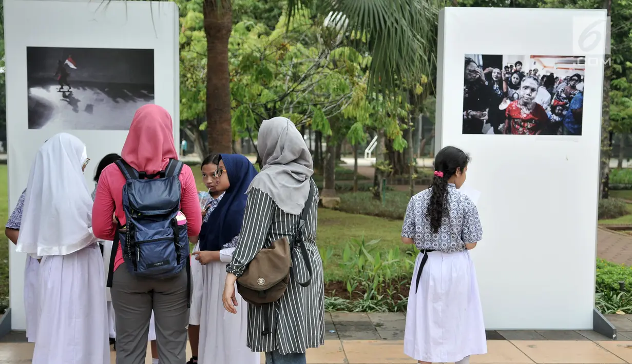Siswa SD Negeri Menteng 01 mengamati karya foto yang dipamerkan dalam pameran fotografi Rekam Jakarta di Taman Menteng, Kamis (29/8/2019). Kegiatan tersebut dalam rangka edukasi bagi siswa mengenal profesi foto jurnalistik. (merdeka.com/Iqbal S Nugroho)