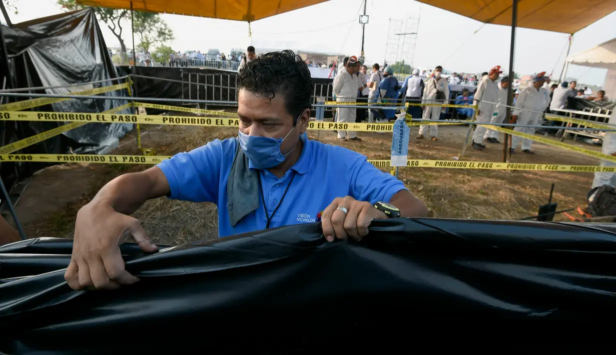 Petugas forensik memakai masker saat proses penggalian kuburan massal di Tetelzingo, Morelos, Meksiko (23/5).Di duga korban yang berada dalam kuburan massal ini adalah korban pembunuhan yang dilakukan komplotan narkoba Meksiko. (ALFREDO ESTRELLA / AFP)