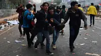 Sejumlah mahasiswa menggotong rekan mereka yang terluka saat demonstrasi menolak pengesahan RUU KUHP dan revisi UU KPK di depan Gedung DPR, Jakarta, Selasa (24/9/2019). Sejumlah mahasiswa tumbang setelah polisi menembakkan gas air mata untuk membubarkan demonstrasi. (ADEK BERRY/AFP)