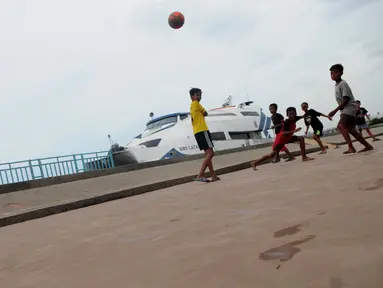 Anak-anak bermain bola di pelataran Pelabuhan Kali Adem, Muara Angke, Jakarta, Rabu (4/1). Mereka yang tinggal di pemukiman sekitar memanfaatkan Pelabuhan Kali Adem sebagai arena bermain selama mengisi masa liburan sekolah. (Liputan6.com/Gempur M Surya)