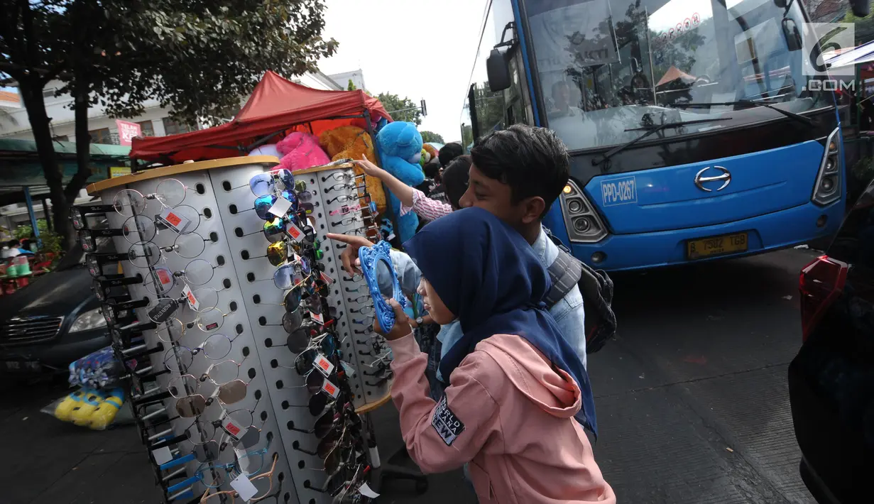 Pengunjung memilih asesoris di sekitar Museum Fatahillah, Jakarta, Rabu (20/6). Libur lebaran 2018, sejumlah PKL memenuhi kawasan Kota Tua Jakarta, akibatnya jalan di sekitar Museum Fatahillah semrawut. (Liputan6.com/Helmi Fithriansyah)