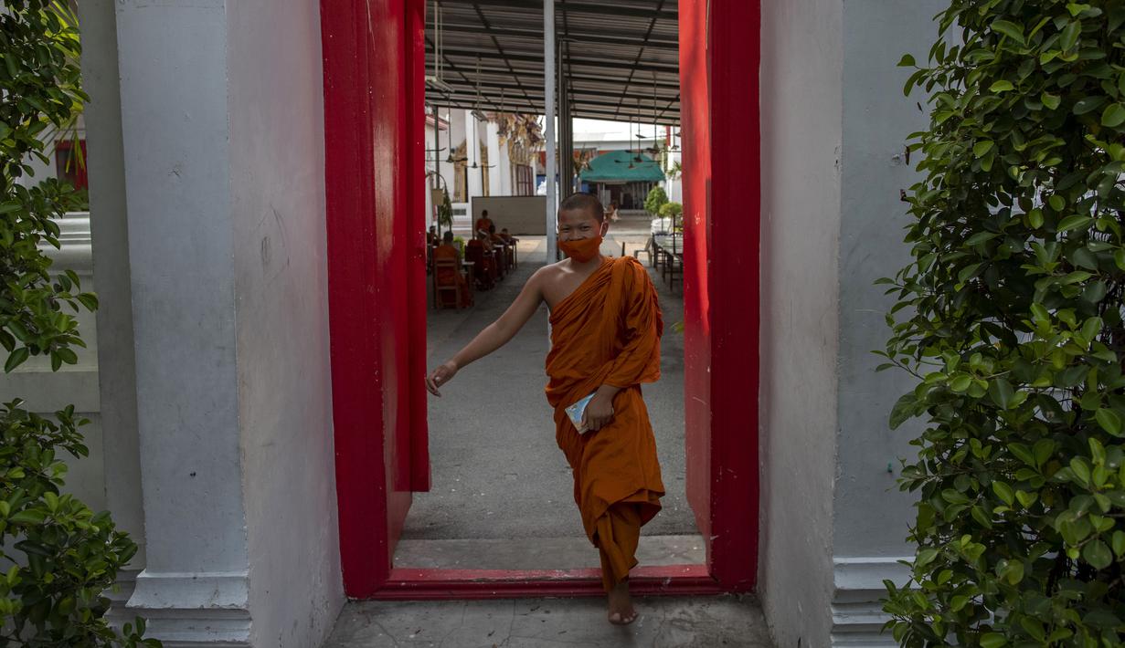 Biksu muda yang mengenakan masker berjalan pergi setelah belajar agama di Molilokayaram Educational Institute, Bangkok, Thailand, Rabu (15/4/2020). Sekitar 200 biksu muda tetap bersekolah kendati Thailand menutup semua sekolah selama lockdown akibat COVID-19. (AP Photo/Gemunu Amarasinghe)