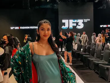 Mengenakan terusan berwarna hijau dipadu outer warna senada, Canti Tachril hadir di JF3. Ia berpose di atas catwalk. (Foto: Instagram/@cantitachril)