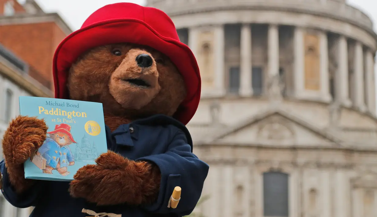 Seseorang yang mengenakan kostum Paddington Bear berpose sambil menunjukkan buku di London, Inggris (30/5). Sesi foto ini untuk mempromosikan peluncuran buku terakhir Michael Bond, Paddington di St Paul's. (AP/Frank Augstein)