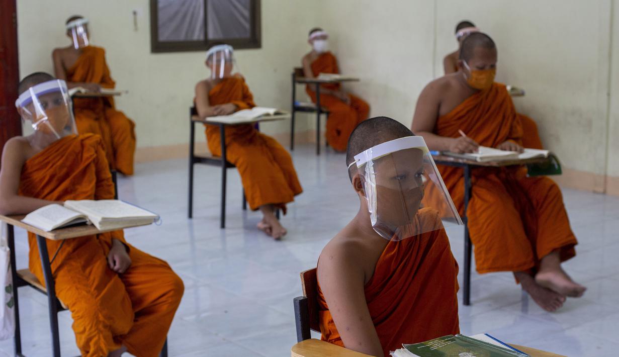 Para biksu muda mengenakan masker dan pelindung wajah saat belajar agama di Molilokayaram Educational Institute, Bangkok, Thailand, Rabu (15/4/2020). Sekitar 200 biksu muda tetap bersekolah kendati Thailand menutup semua sekolah selama lockdown akibat COVID-19. (AP Photo/Gemunu Amarasinghe)