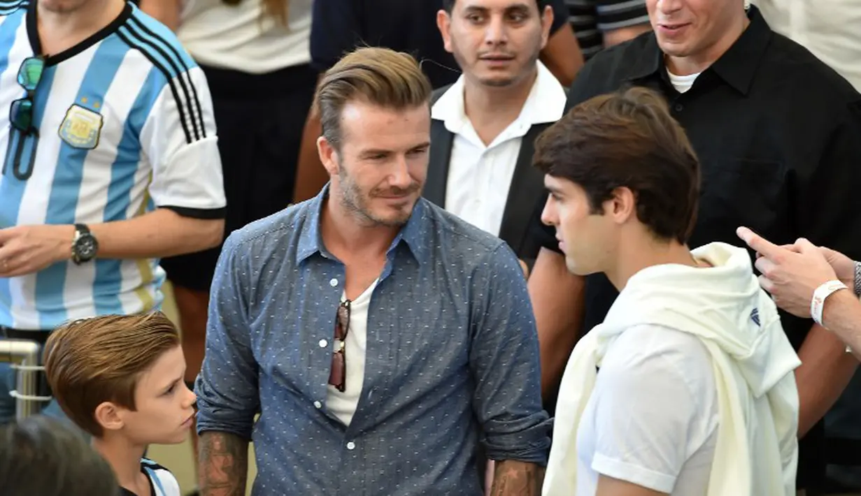 Suami Victoria Beckham itu (tengah) tampil santai dengan mengenakan kaus putih berpadu kemeja denim di stadion Maracana, Brasil, Senin (14/7/14). (AFP PHOTO/Nelson Almeida)