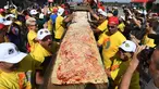 Peserta menunjukan pizza yang telah selesai dibuat di jalur Auto Club Speedway, di Fontana, California (10/6). Mereka berhasil memecahkan rekor Guinness World Records untuk pizza terpanjang di dunia dengan panjang 1,32 mil atau 2,13 km. (AFP/Mark Ralston)