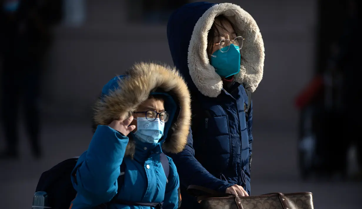 Para pemudik yang memakai masker berjalan menuju pintu masuk Stasiun Kereta Api Beijing di Beijing, China, Sabtu (14/1/2023). Jutaan warga China diperkirakan akan melakukan perjalanan selama periode liburan Tahun Baru Imlek tahun ini. (AP Photo/Mark Schiefelbein)