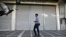 Seorang pria berjalan melintasi sebuah bank yang berhenti beroperasi di Athena, Yunani, (29/6/2015). Seperti dikutip BBC, penarikan uang pun dibatasi hanya 60 euro per hari. (REUTERS/Marko Djurica)