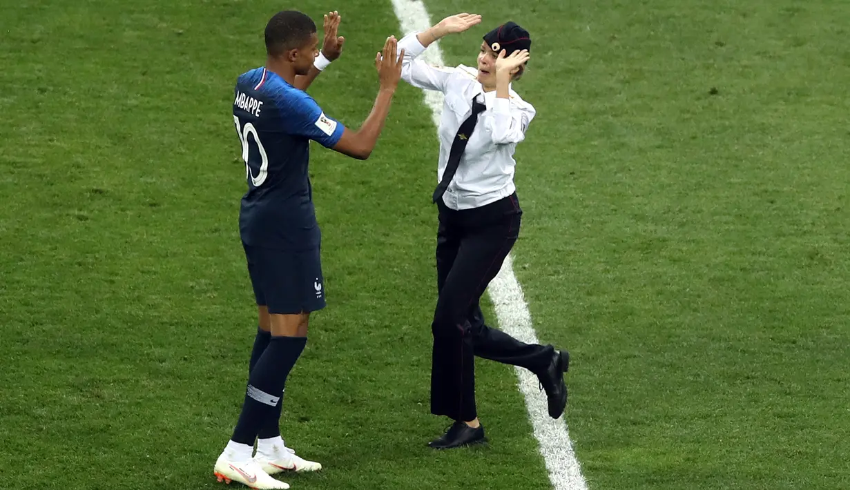 Seorang penyusup melakukan tos dengan pemain timnas Prancis Kylian Mbappe pada laga final Piala Dunia 2018 melawan Kroasia di Luzhniki Stadium, Minggu (15/7). Penyusup masuk ke tengah lapangan saat pertandingan memasuki menit 52. (AP/Thanassis Stavrakis)