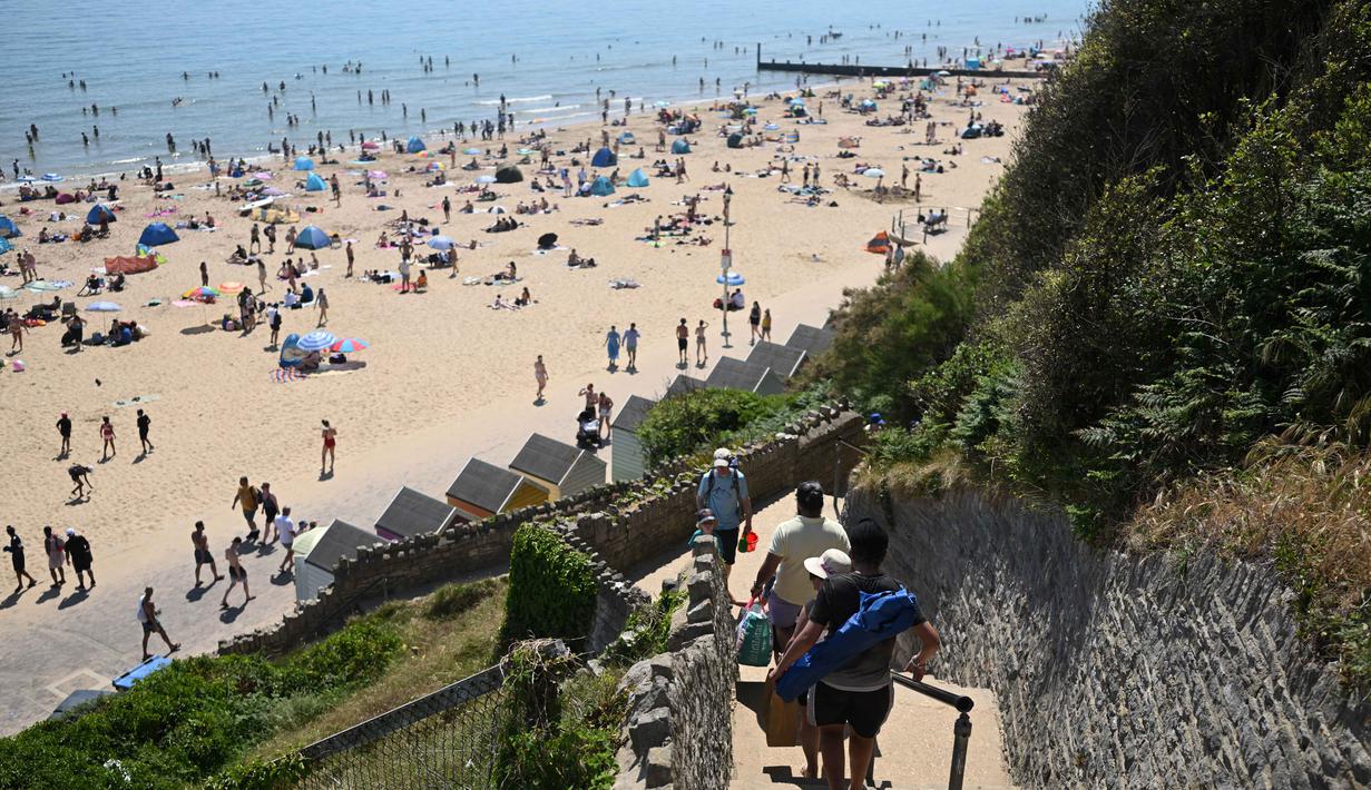 Orang-orang menuruni tangga menuju Pantai Bournemouth, Selatan Inggris pada Selasa 26 Mei 2026, saat kondisi gelombang panas menyebar ke sebagian wilayah tenggara Inggris dan London. (JUSTIN TALLIS/AFP)