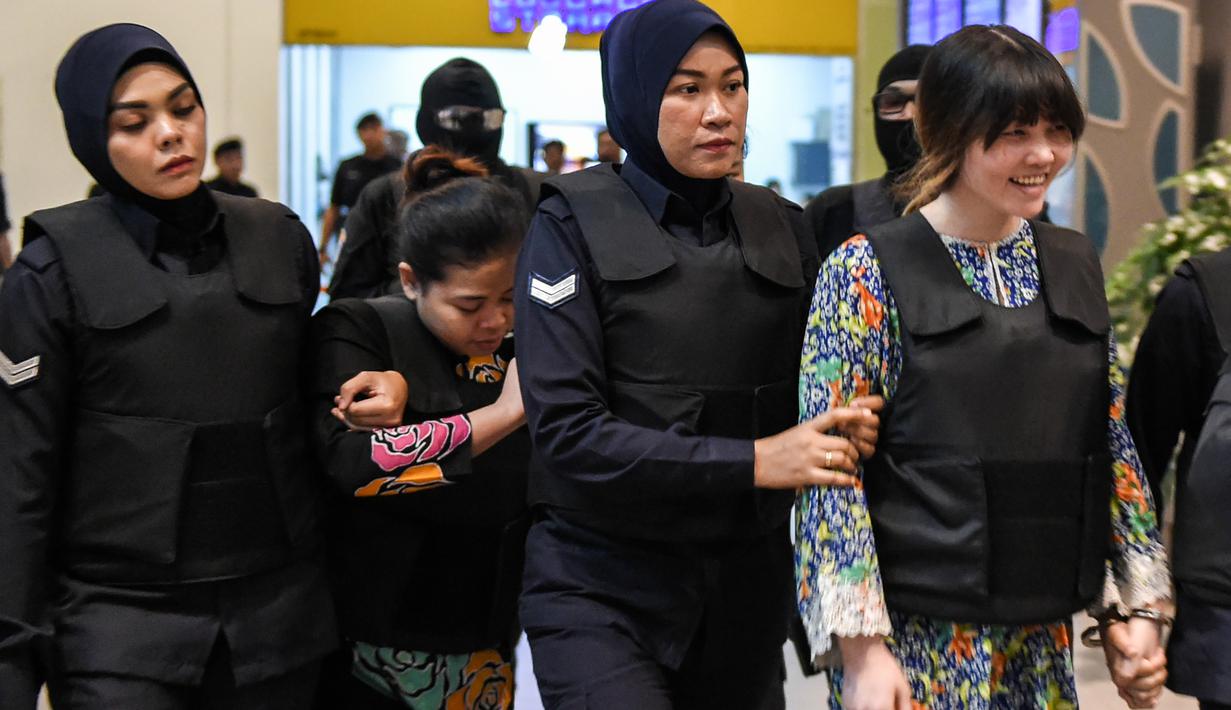 Tersangka kasus pembunuhan Kim Jong-nam, Siti Aisyah dan Doan Thi Huong, dikawal polisi menuju Bandara Internasional Kuala Lumpur, Selasa (24/10). Keduanya melakukan reka ulang kejadian di tempat keduanya dituding meracuni Kim Jong-nam. (MOHD RASFAN/AFP)