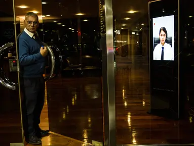 Seorang porter keluar dari pintu sebuah gedung di Buenos Aires, Argentina, Jumat (13/4). Argentina mulai menerapkan penjaga keamanan virtual di sujumlah gedung. (AP Photo/Rodrigo Abd)