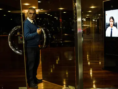 Seorang porter keluar dari pintu sebuah gedung di Buenos Aires, Argentina, Jumat (13/4). Argentina mulai menerapkan penjaga keamanan virtual di sujumlah gedung. (AP Photo/Rodrigo Abd)