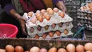 Pedagang memindahkan telur ayam dagangannya di Pasar Kelapa Dua, Kabupaten Tangerang, Banten, Rabu (29/12/2021). Meroketnya harga telur ayam di sejumlah wilayah jelang pergantian tahun dipicu oleh harga pakan yang tinggi. (Liputan6.com/Angga Yuniar)