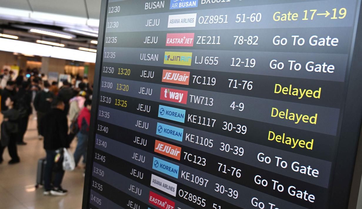 Penumpang berjalan melewati papan informasi yang menampilkan penerbangan tertunda di Bandara Gimpo, Seoul, pada Kamis 13 November 2025, pada hari ujian masuk perguruan tinggi tahunan yang dikenal secara lokal sebagai Suneung. (Jung Yeon-je/AFP)