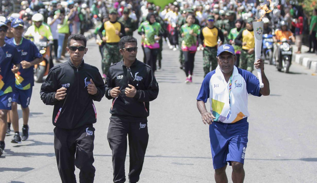 Legenda taekwondo Indonesia, Abdul Rojak, membawa obor Asian Games saat melintasi di Banjarmasin, Kalimantan Selatan, Senin (30/7/2018). Sebanyak 53 kota di Indonesia akan dilalui oleh obor Asian Games. (Bola.com/Reza Bachtiar)