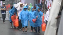 Pendukung capres nomor urut 01 Joko Widodo diguyur hujan saat tiba di Sentul International Convention Center, Bogor, Jawa Barat, Minggu (24/2). Jokowi bakal menyampaikan pidato politik di hadapan 40.000 pendukungnya. (Liputan6.com/Herman Zakharia)