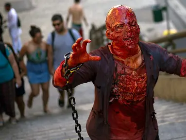 Peserta berdandan layaknya zombie dan menakut-nakuti orang selama acara Zombie Walk di Sao Paulo, Brasil, Sabtu (2/11/2019). Ratusan orang turun ke jalan memakai kostum karakter horor pada acara tahunan yang digelar sejak 2006 pada Hari Para Arwah. (Miguel SCHINCARIOL / AFP)