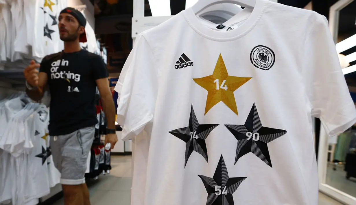 Salah satu petugas toko di Frankfurt, (14/7/2014), melintas diantara kaos-kaos berlogo federasi sepak bola Jerman dengan empat bintang. (REUTERS/Ralph Orlowski)