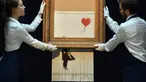 Karyawan berpose dengan lukisan "Girl with Balloon" di rumah lelang Sotheby London, 12 Oktober 2018. Lukisan karya seniman Bansky itu rusak menjadi potongan-potongan saat terjual seharga sekitar Rp 20 miliar pada lelang 5 Oktober 2018. (BEN STANSALL/AFP)