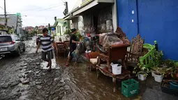 Warga membersihkan rumah mereka setelah banjir akibat Topan Goni yang melanda Kota Batangas di selatan Manila, Filipina, Senin (2/11/2020). Badan Bencana Negara mencatat sedikitnya 16 orang tewas akibat topan terkuat di dunia tahun ini, yang menghantam Filipina pada hari Minggu. (TED ALJIBE / AFP)