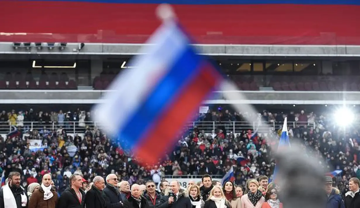 Seorang peserta mengibarkan bendera Rusia saat mendegarkan pidato Vladimir Putin dalam sebuah kampanye di stadion Luzhniki di Moskow (3/3). Putin pun telah bersiap untuk memperoleh periode keempatnya sebagai presiden Rusia. (AFP/Kirill Kudryavtsev)