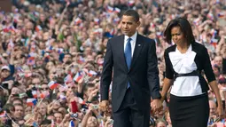 Presiden Amerika Serikat (AS) ke-44, Barack Obama menggandeng tangan sang istri, Michelle Obama, saat berjalan menuruni podium usai menyampaikan pidato di Hradcany Square, dekat Kastil Praha Republik Ceko, 5 April 2009. (AFP PHOTO / SAUL LOEB)