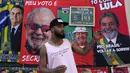 Jose Lucas da Silva berdiri di depan handuk bergambar Presiden Brasil Jair Bolsonaro (kiri) dan mantan Presiden Brasil Luiz Inacio da Silva atau Lula yang dia jual menjelang pemilihan umum presiden di Rio de Janeiro, Brasil, 27 Juli 2022. Ada dua calon yang diunggulkan pada pemilihan umum presiden di Brasil. (AP Photo/Silvia Izquierdo)