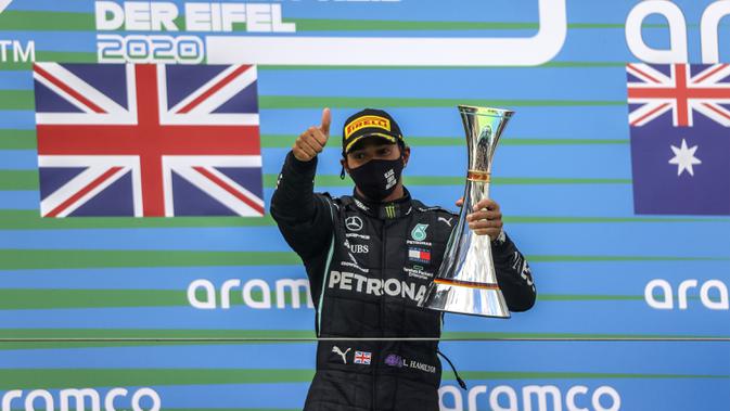 Pembalap Mercedes Lewis Hamilton memegang trofi setelah memenangkan F1 GP Eifel di Nuerburgring, Nuerburg, Jerman, Minggu (11/10/2020). Hamilton dengan 91 kemenangannya menyamai legenda F1 Michael Schumacher. (Wolfgang Rattay, Pool via AP)