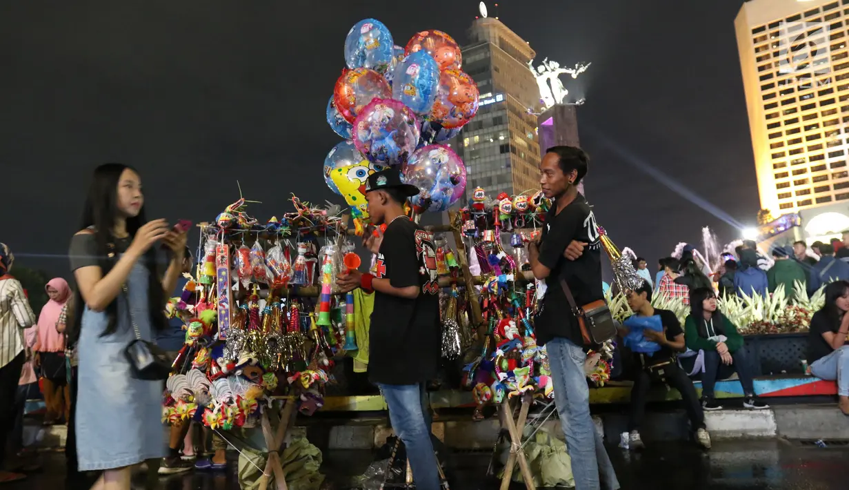 Pedagang menjual terompet dan balon pada malam pergantian tahun di kawasan Bundaran HI, Jakarta, Senin (31/12). Pergantian tahun dimanfaatkan pedagang untuk mencari keuntungan dengan berjualan pernak pernik tahun baru.(Liputan6.com/Angga Yuniar)