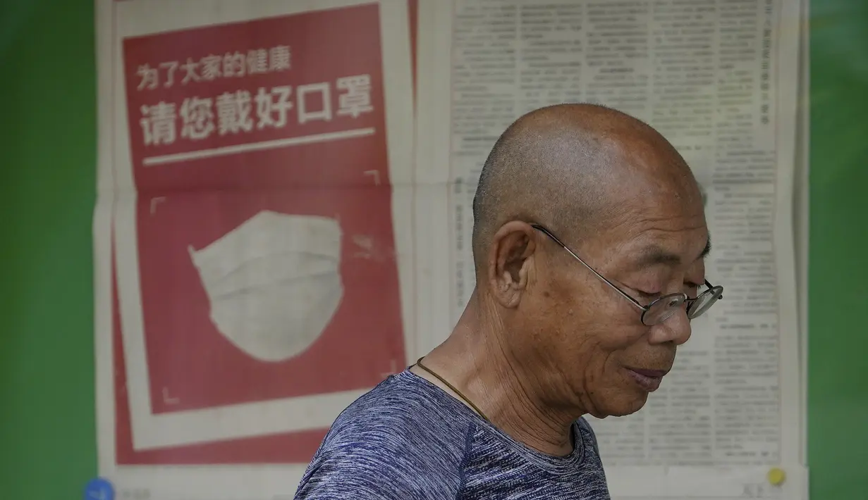 Seorang pria berjalan di dekat koran yang menampilkan iklan yang menyarankan orang untuk memakai masker, di sebuah kios di Beijing pada Senin, 23 Mei 2022. Beijing memperpanjang perintah bagi pekerja dan siswa untuk tinggal di rumah dan memerintahkan pengujian massal tambahan pada hari Senin untuk membendung kasus COVID-19 yang kembali meningkat di ibu kota China. (AP Photo/Andy Wong)