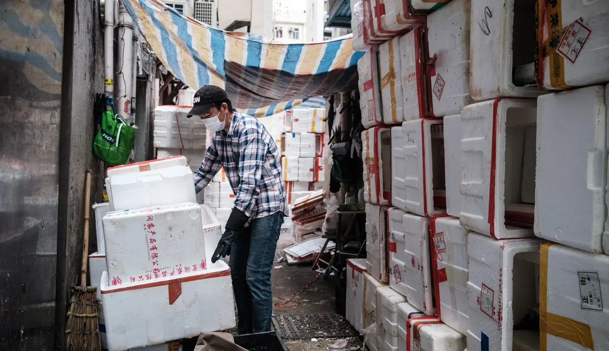 Seorang pekerja memakai masker sebagai tindakan pencegahan terhadap virus corona COVID-19 menumpuk kotak polystyrene di dekat toko yang menjual buah-buahan dan sayuran di Hong Kong (21/4/2020).  (AFP/Anthony Wallace)